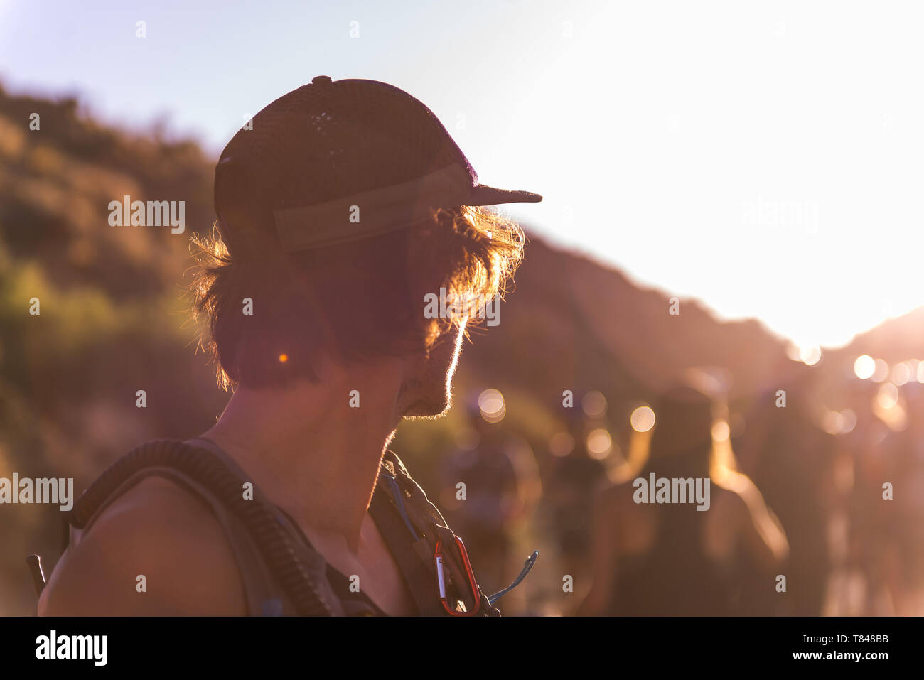 L'homme à casquette regardant par-dessus son épaule au groupe de personnes,  coucher du soleil Photo Stock - Alamy