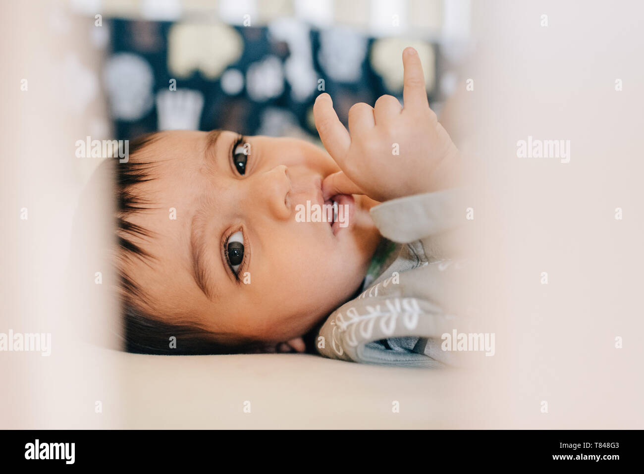 Baby Boy lying awake and sucking thumb dans la huche, portrait Banque D'Images