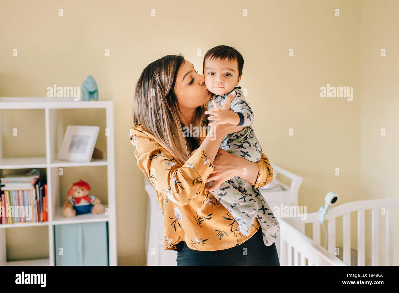 Mère embrassant bébé fils en pépinière, portrait Banque D'Images