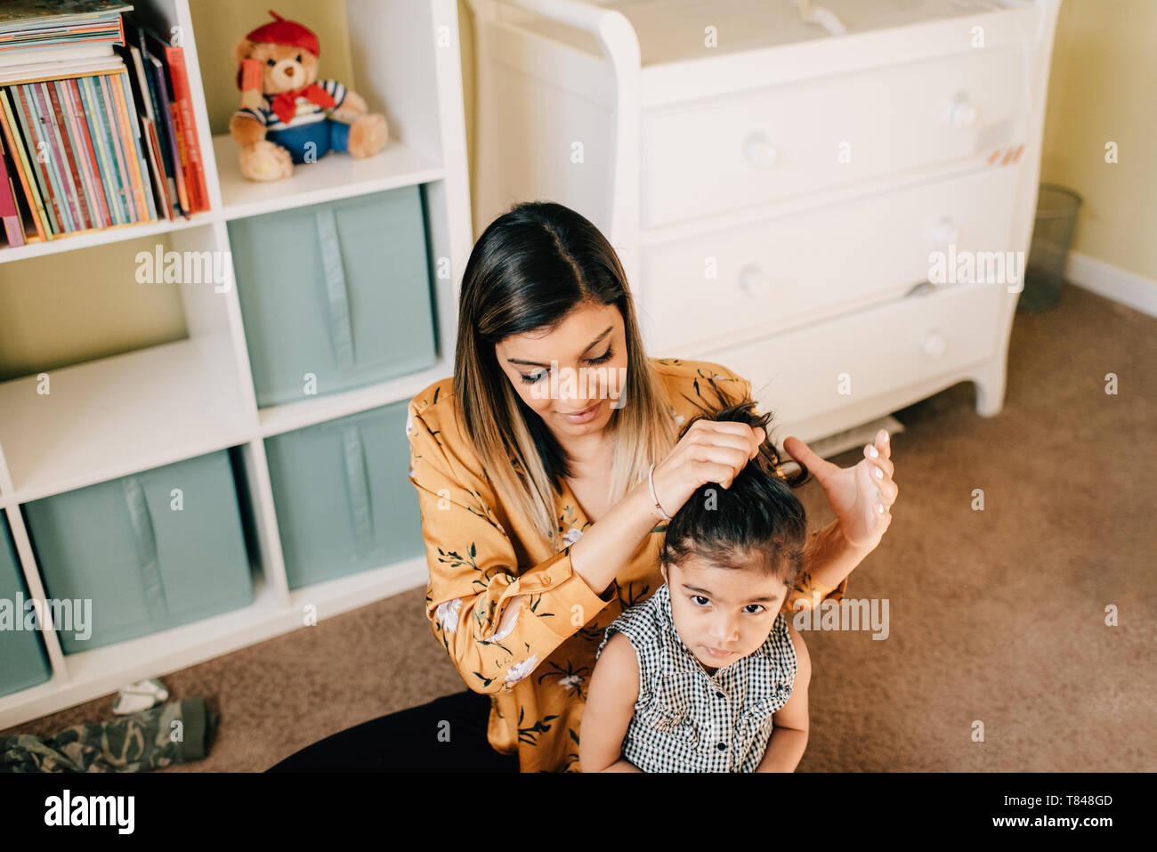 Fille assise sur les jardins d'étage tandis que ses cheveux styling mère Banque D'Images