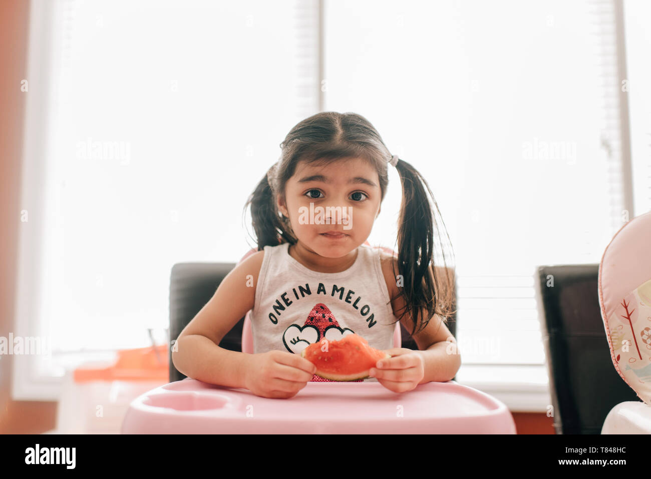 Fille dans une chaise haute holding water melon, portrait Banque D'Images