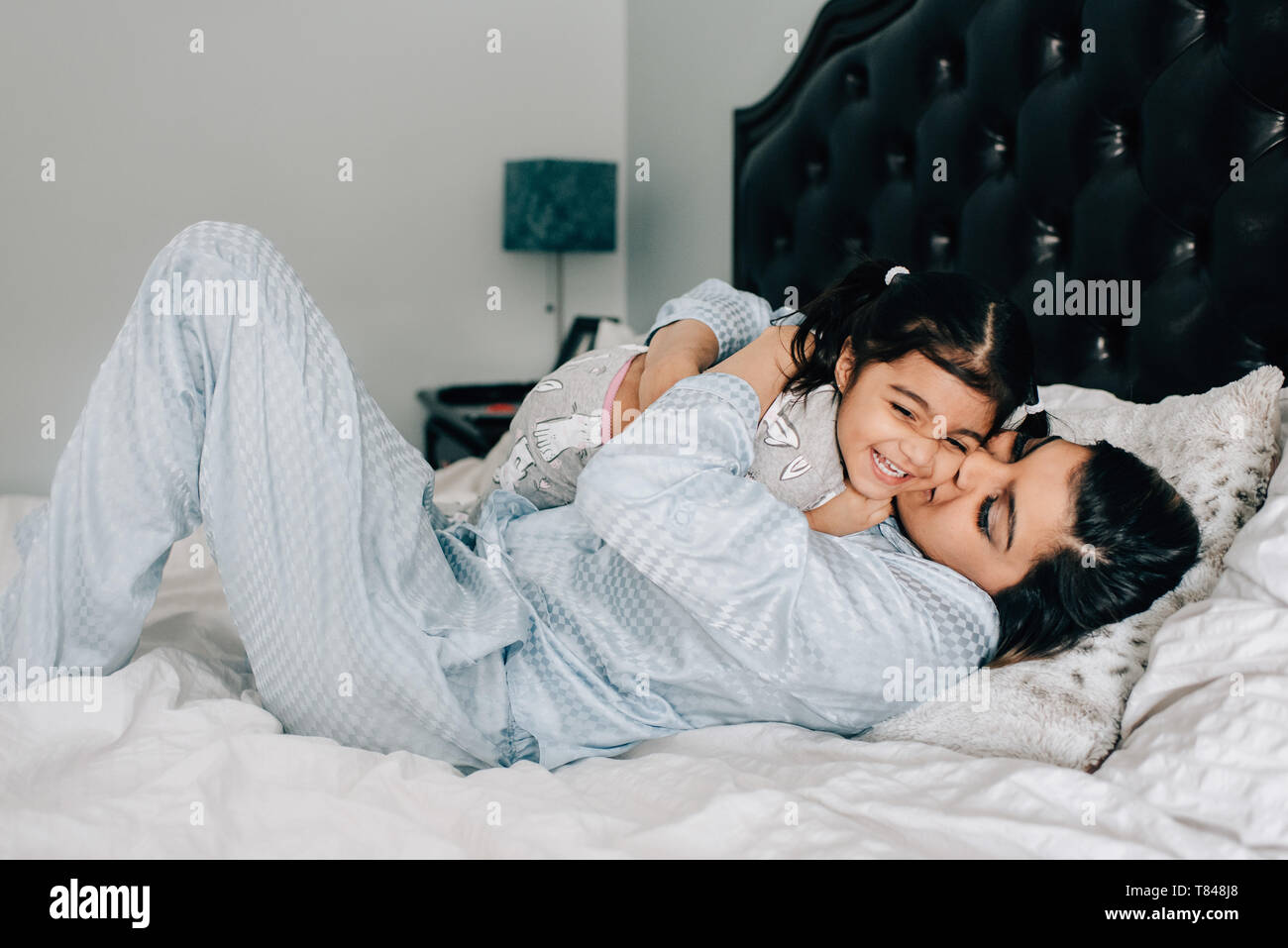 Fille et mère hugging on lit dans la matin Banque D'Images