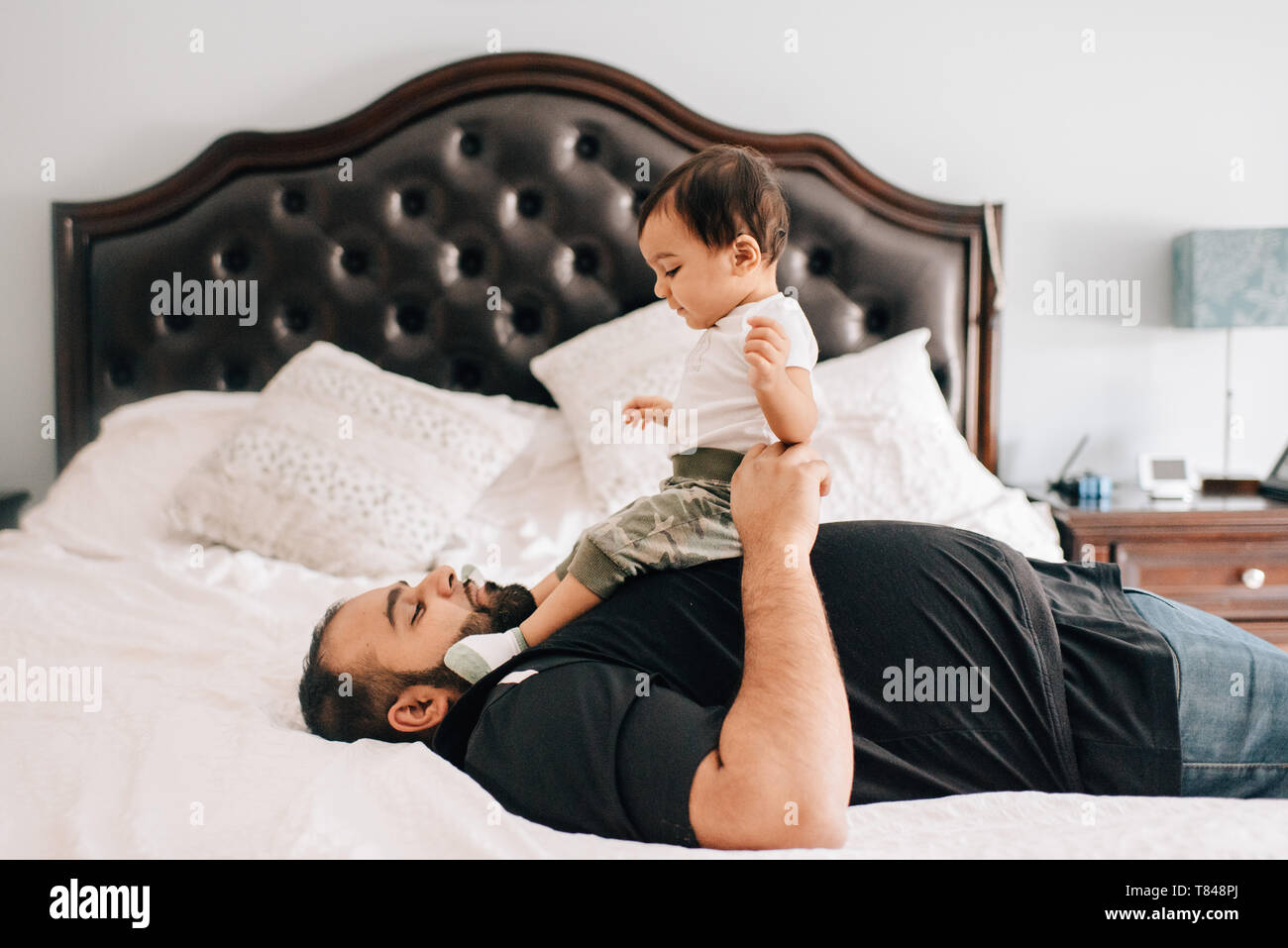 Père lying on bed with baby son sur sa poitrine Banque D'Images