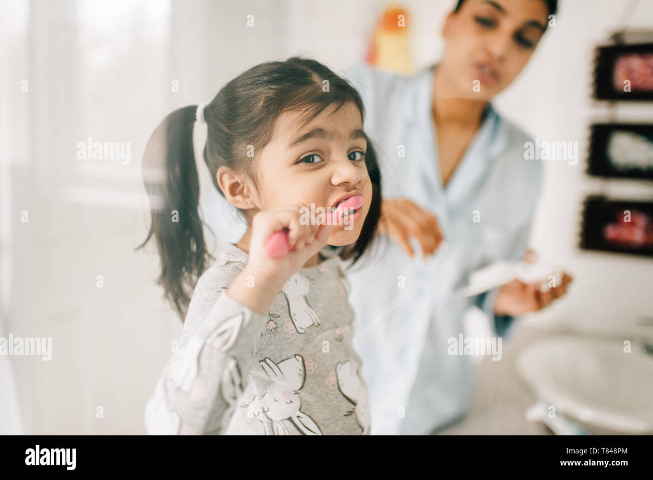 Fille avec la mère se brosser les dents dans la salle de bains Banque D'Images