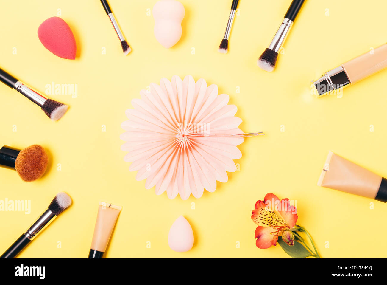 Mise à plat de fête d'arrangement pour les produits de maquillage et cosmétiques pinceaux teint sur fond jaune. Banque D'Images