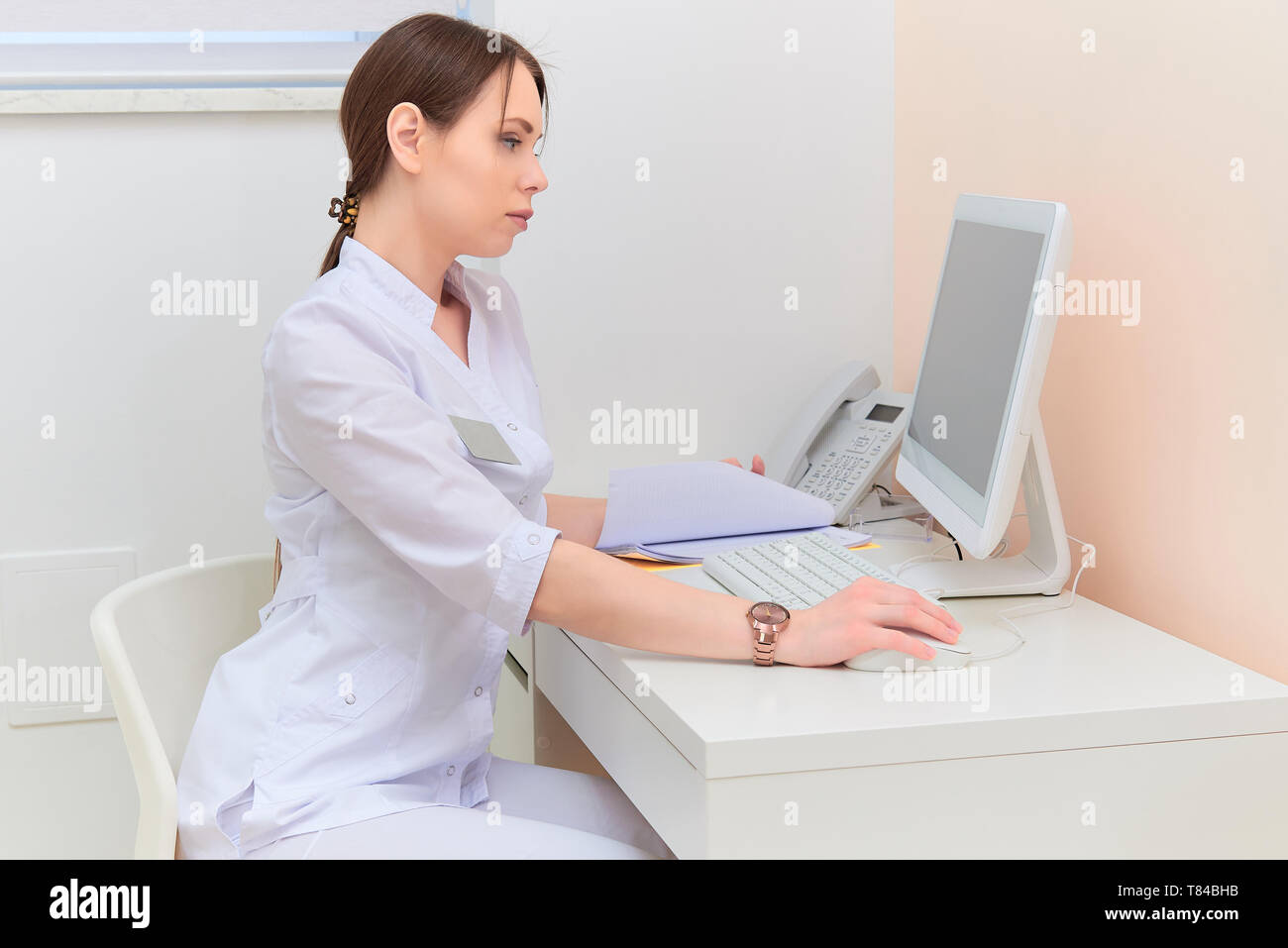 Médecin concentré avec rapport à la recherche à l'écran d'ordinateur au bureau en bureau médical. Banque D'Images