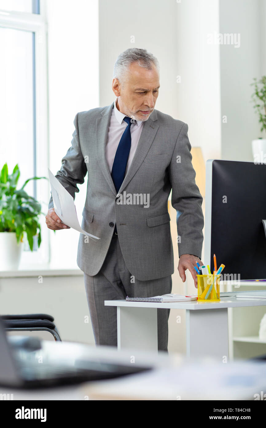 Strict curieux homme aux cheveux gris en costume gris et cravate noire  Photo Stock - Alamy