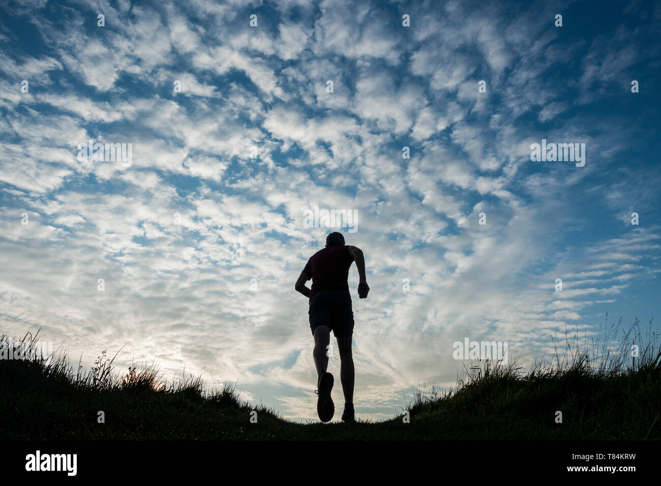 Low angle view of mature trail runner tournant au lever du soleil. UK Banque D'Images