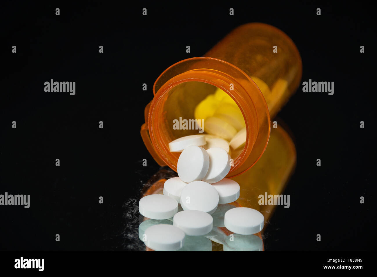 White prescription pills et bouteille en plastique orange sur miroir Banque D'Images