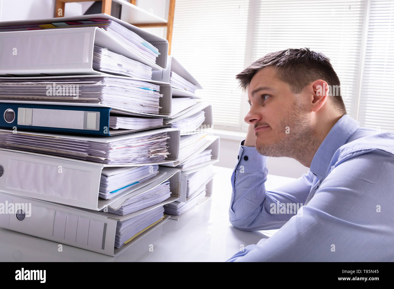 Vue arrière du souligné Businesswoman Pointing en face de dossiers empilés Banque D'Images