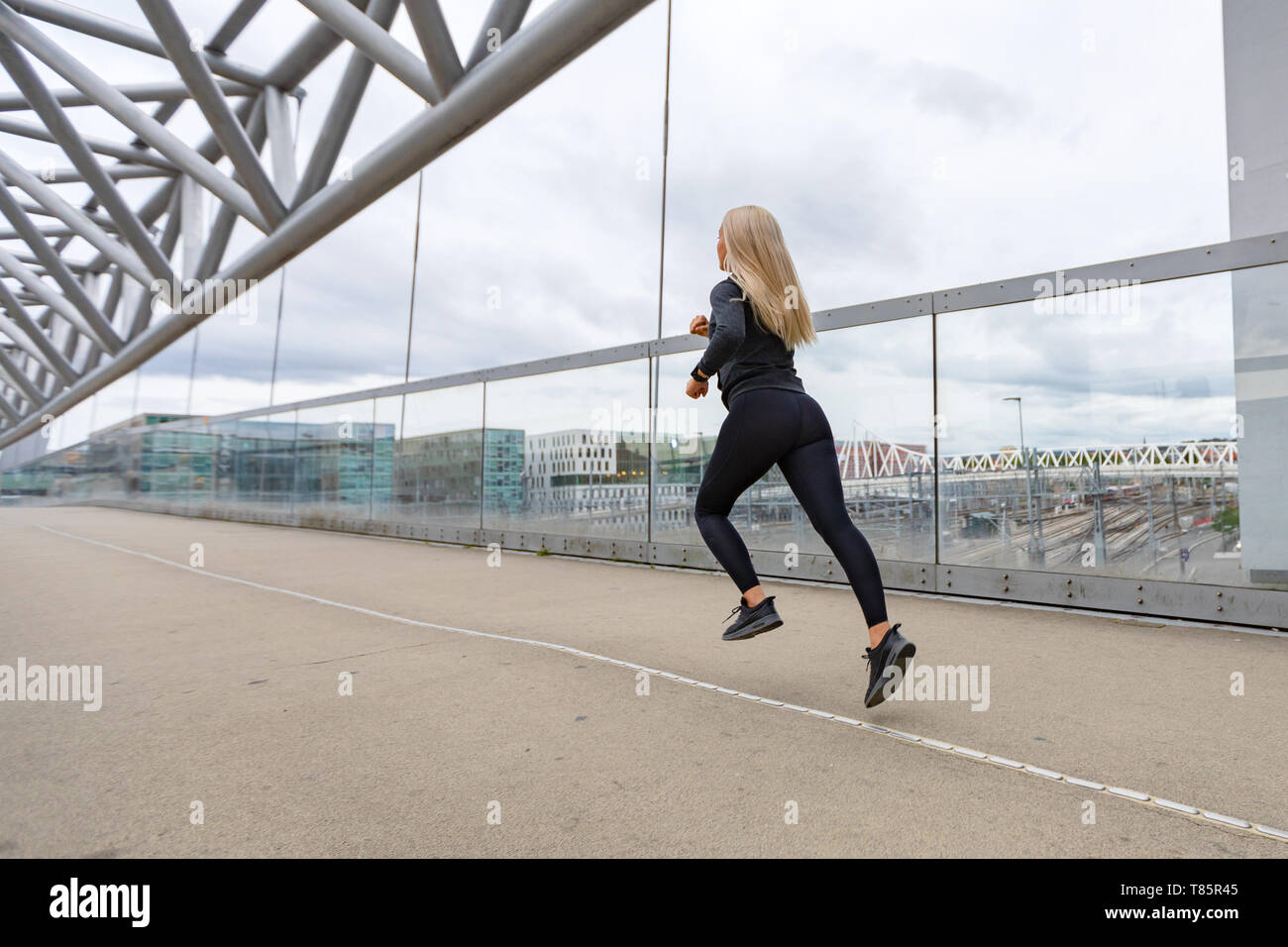 Course rapide sporty woman in black en tenue d'entraînement de l'environnement de la ville moderne Banque D'Images