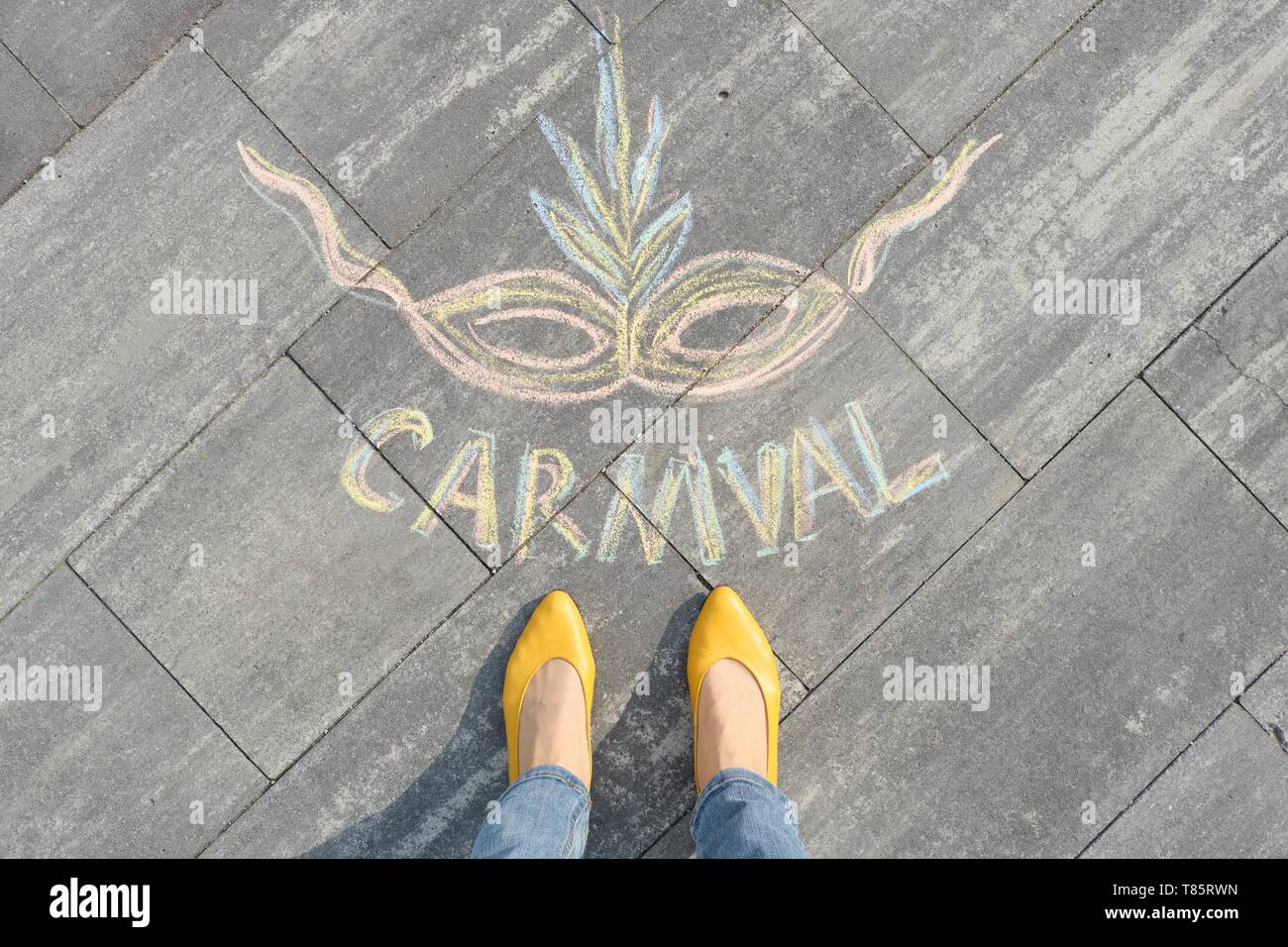 Carnival written on gris trottoir avec les jambes des femmes dans les chaussures jaunes, vue du dessus Banque D'Images