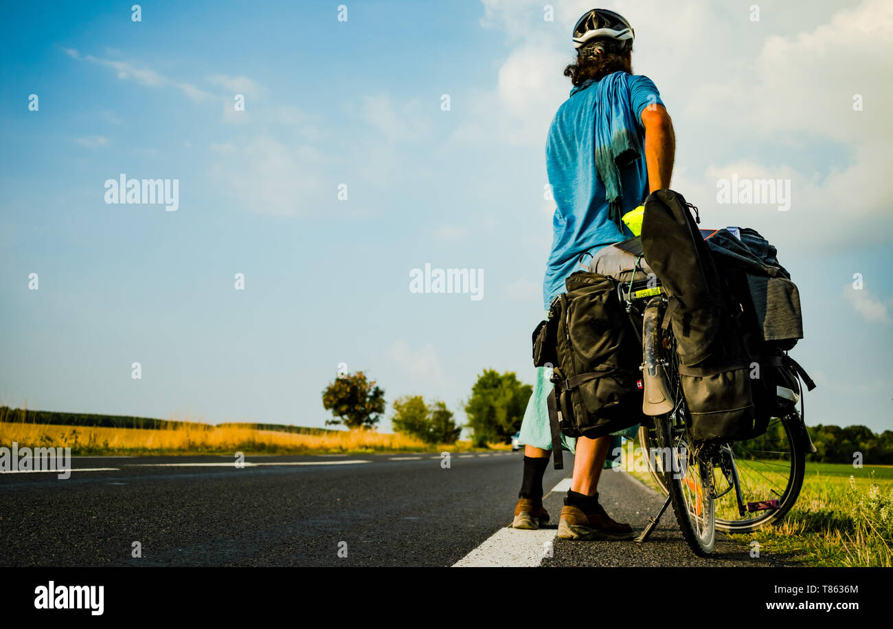 Cyclotourist orienté vers l'arrière et regarder une longue route devant lui. Banque D'Images