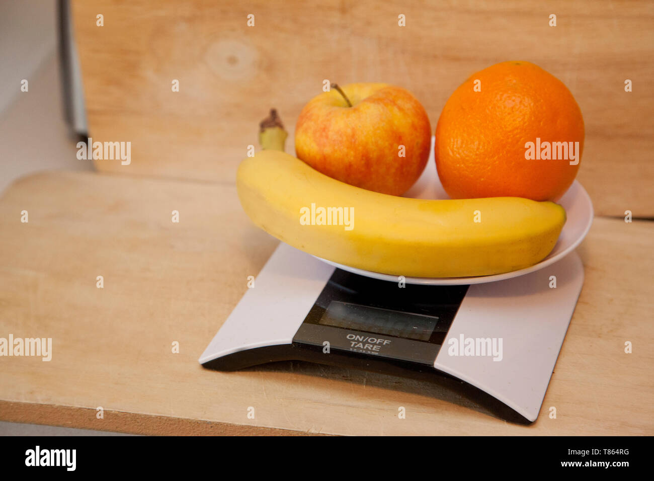 Une pomme, une banane et d'orange sur une échelle numérique à peser Banque D'Images
