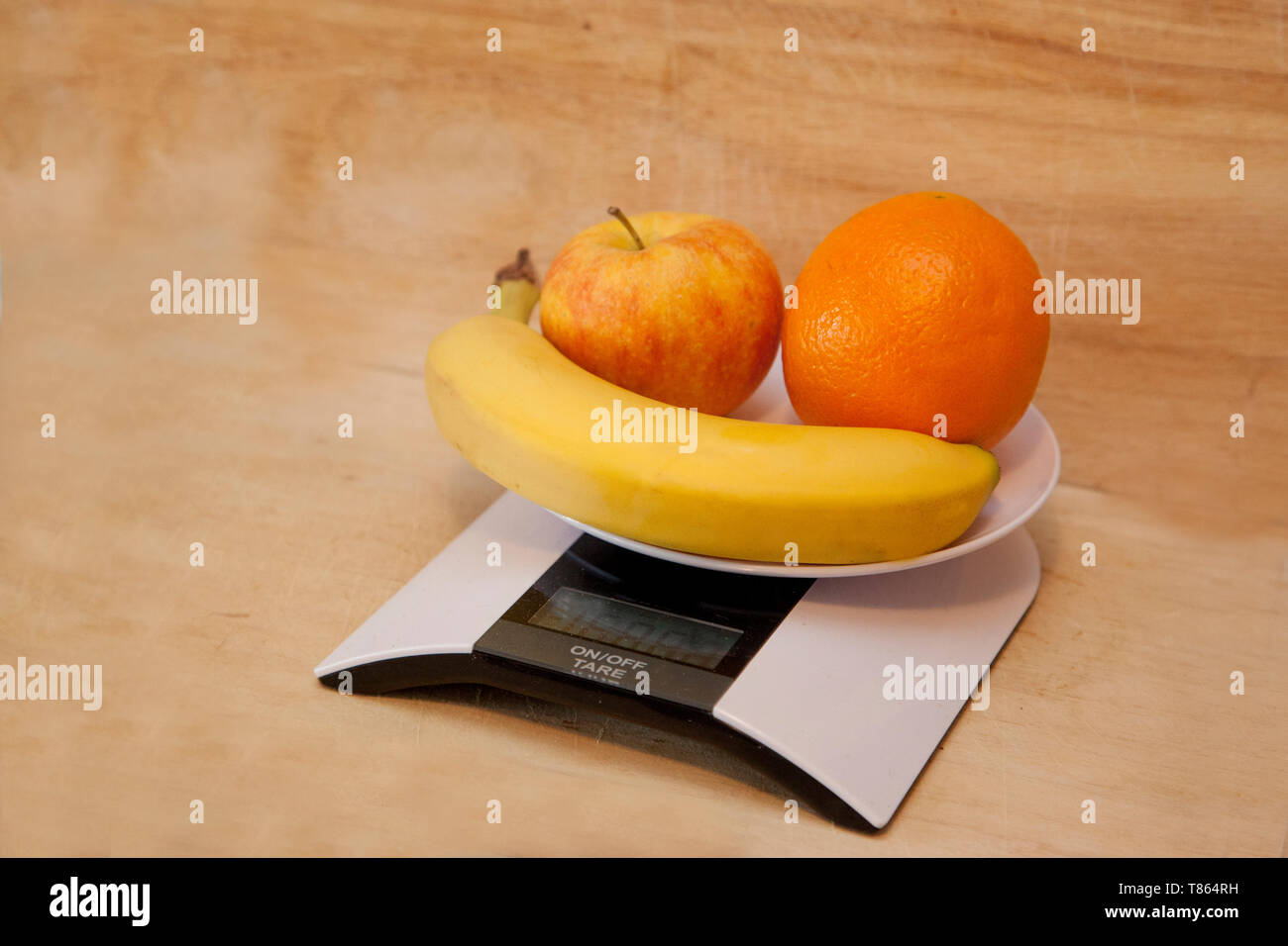 Banane, orange et apple sur une échelle numérique étant pesé comme un choix santé Banque D'Images