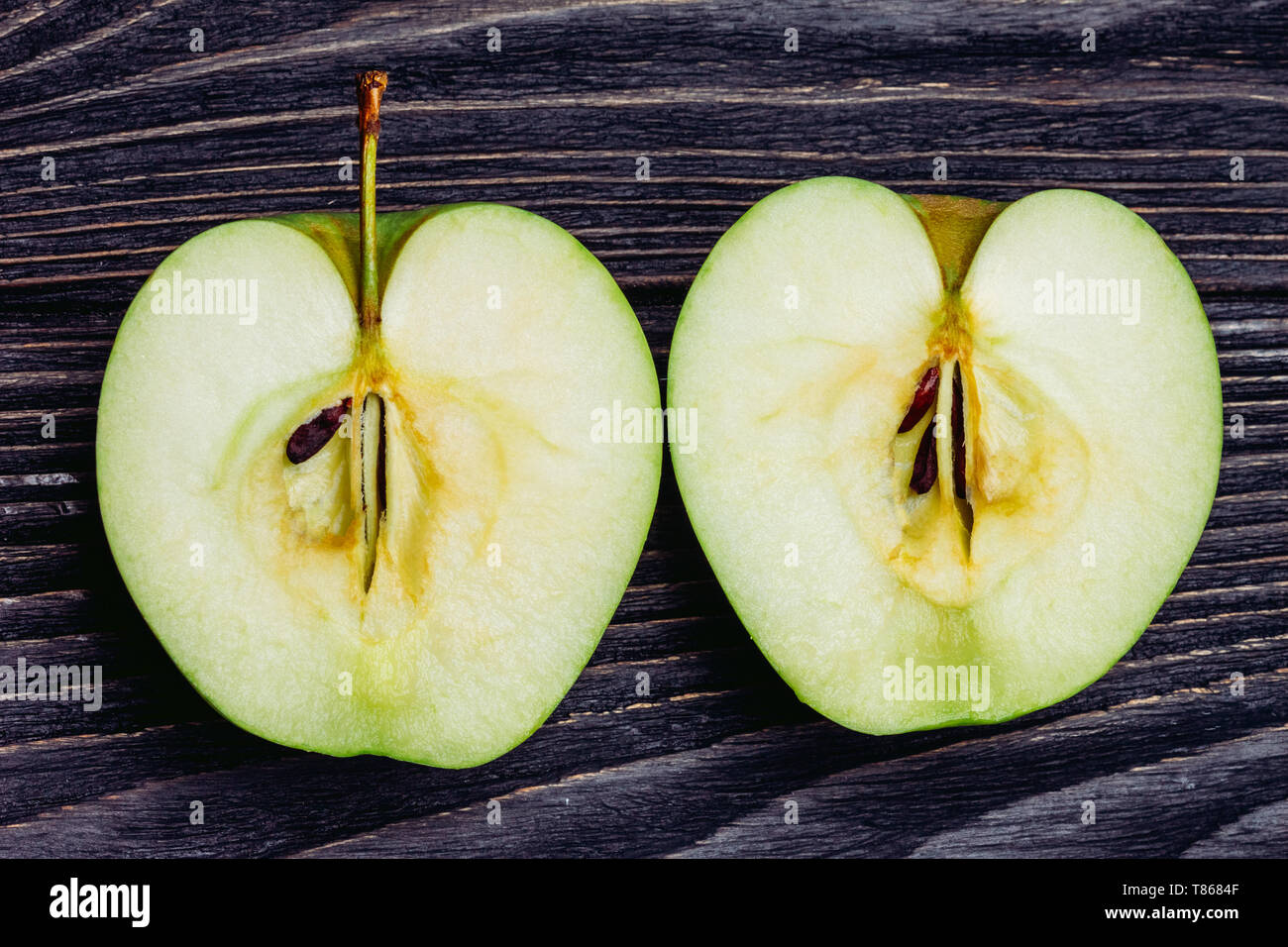 Pomme mûre sur une table de bois coupé en deux Banque D'Images