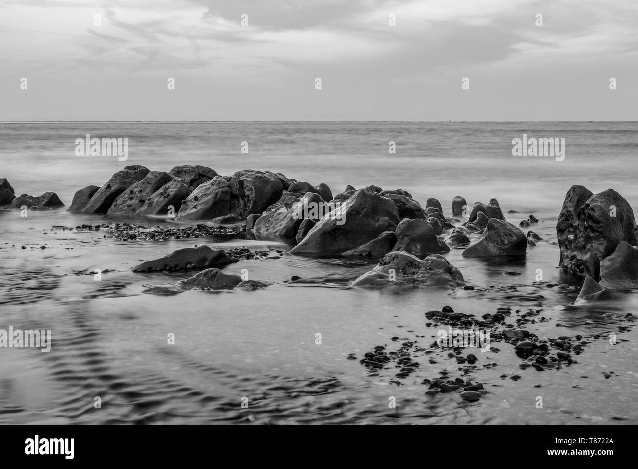 Le noir et blanc d'une longue exposition de monticules de boue par shingle street front de mer Banque D'Images