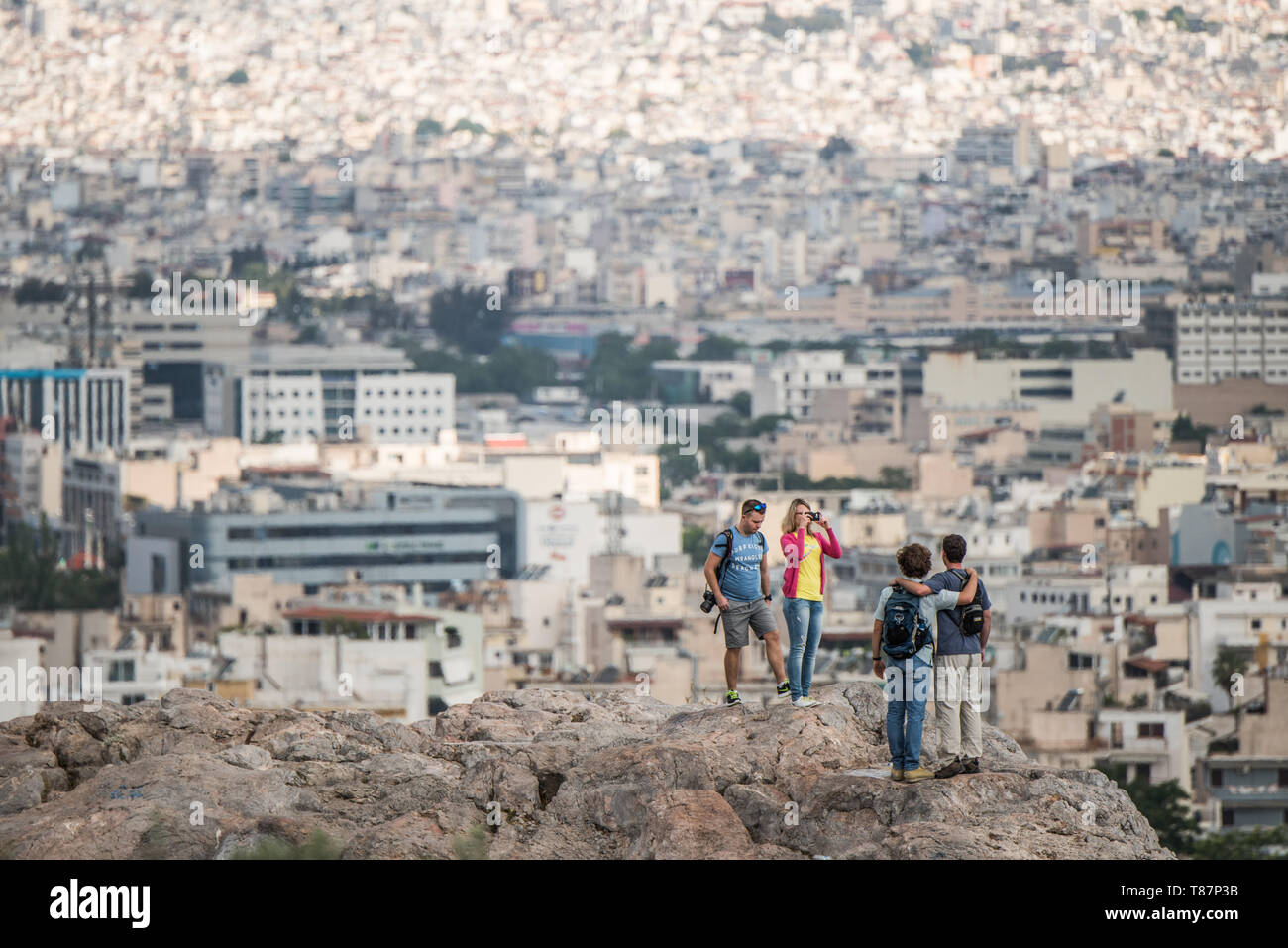 Les touristes de la colline de l'Acropole surplombant la ville d'Athènes Grèce / ATHÈNES, Grèce - les touristes se tiennent sur la colline de l'Acropole, en prenant dans une large vue sur le paysage urbain tentaculaire d'Athènes ci-dessous. La colline est le site de l'ancienne Acropole, un site classé au patrimoine mondial de l'UNESCO dont les structures classiques - y compris le Parthénon, l'Érechthéion et le temple d'Athéna Nike - datent principalement du Ve siècle av. J.-C. Le point de vue élevé offre l'un des panoramas les plus complets de la capitale grecque et de sa région Attique environnante. Banque D'Images
