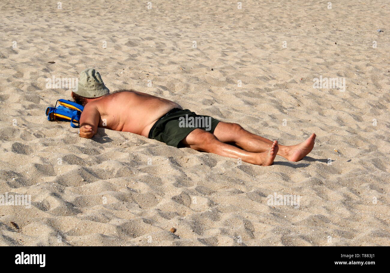 Homme avec chapeau sur son visage allongé sur une plage de sable fin, la Corse, France Banque D'Images