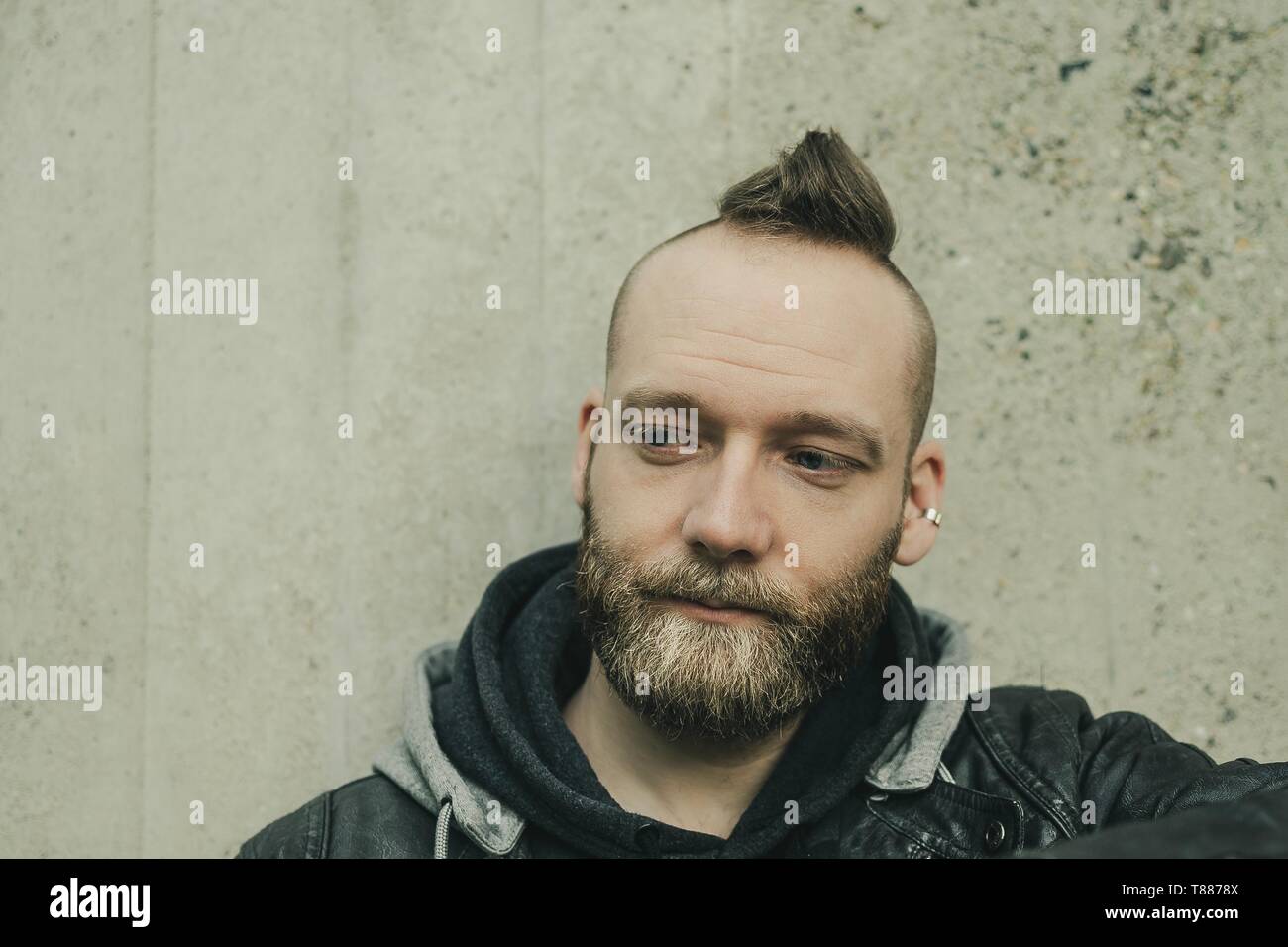 Homme barbu à la pensée vers le bas en face d'un mur Banque D'Images