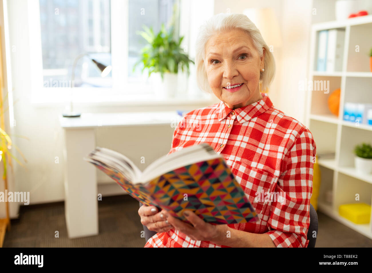 Femme aux cheveux gris positif tenant un livre Banque D'Images