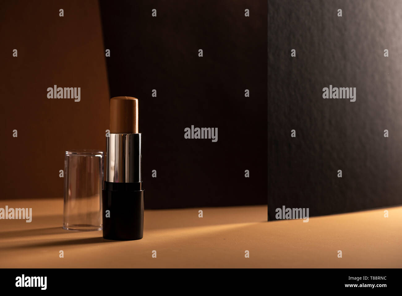 Stick correcteur, sur fond géométrique, dans des tons de brun. Produit et concept de maquillage. Banque D'Images