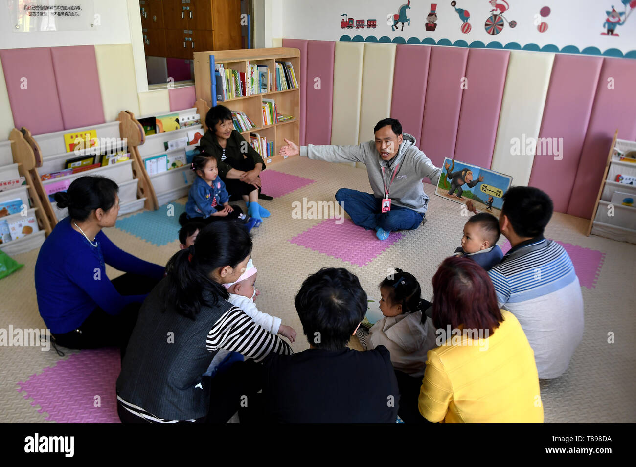 (190512) -- NINGSHAN, 12 mai 2019 (Xinhua) -- le professeur Yue Youlin raconte des histoires avec un livre d'images pour enfants en centre de bébé No.1 Chengguan Township, Ningshan County, au nord-ouest de la province de Shaanxi en Chine le 11 mai 2019. Situé en plein cœur de la montagnes Qinling, Ningshan est un comté pauvre soutenus par l'état. Un projet expérimental, qui offre gratuitement l'éducation précoce de nourrissons de moins de trois ans et d'une formation gratuite de la parentalité est en cours ici. Il vise à aider les enfants vivant dans les régions pauvres pour mieux grandir. Plus de 1 000 enfants ont bénéficié de Ningshan Banque D'Images