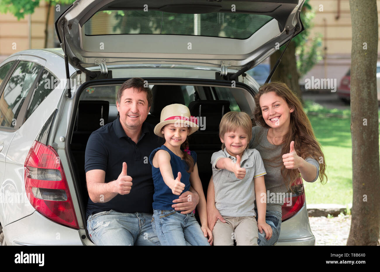 Happy Family sitting dans le coffre d'une voiture et showing Thumbs up . Le concept de voyage en famille Banque D'Images