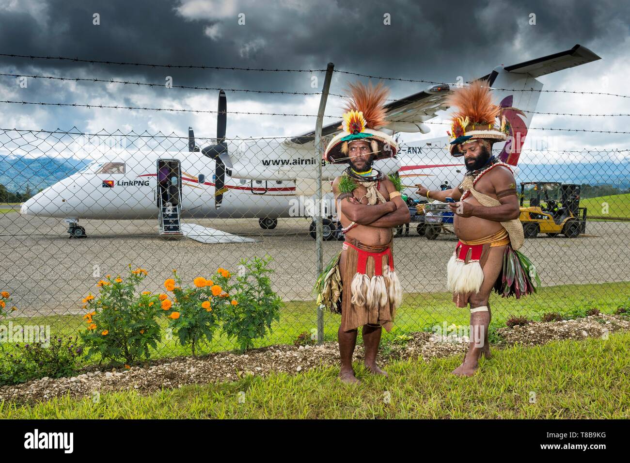 La Papouasie-Nouvelle-Guinée, province, Hela, tribu Huli zone, Kobe Tumbiali Tari village, danseurs prêt pour un sing-Sing (fête traditionnelle) à l'atterrissage à la recherche à un Tari Niugini Air avion Banque D'Images