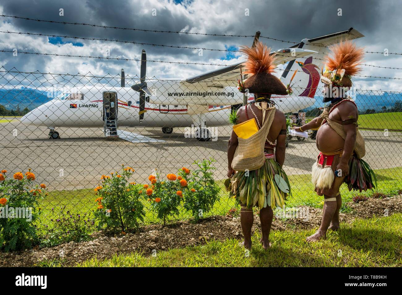 La Papouasie-Nouvelle-Guinée, province, Hela, tribu Huli zone, Kobe Tumbiali Tari village, danseurs prêt pour un sing-Sing (fête traditionnelle) à l'atterrissage à la recherche à un Tari Niugini Air avion Banque D'Images