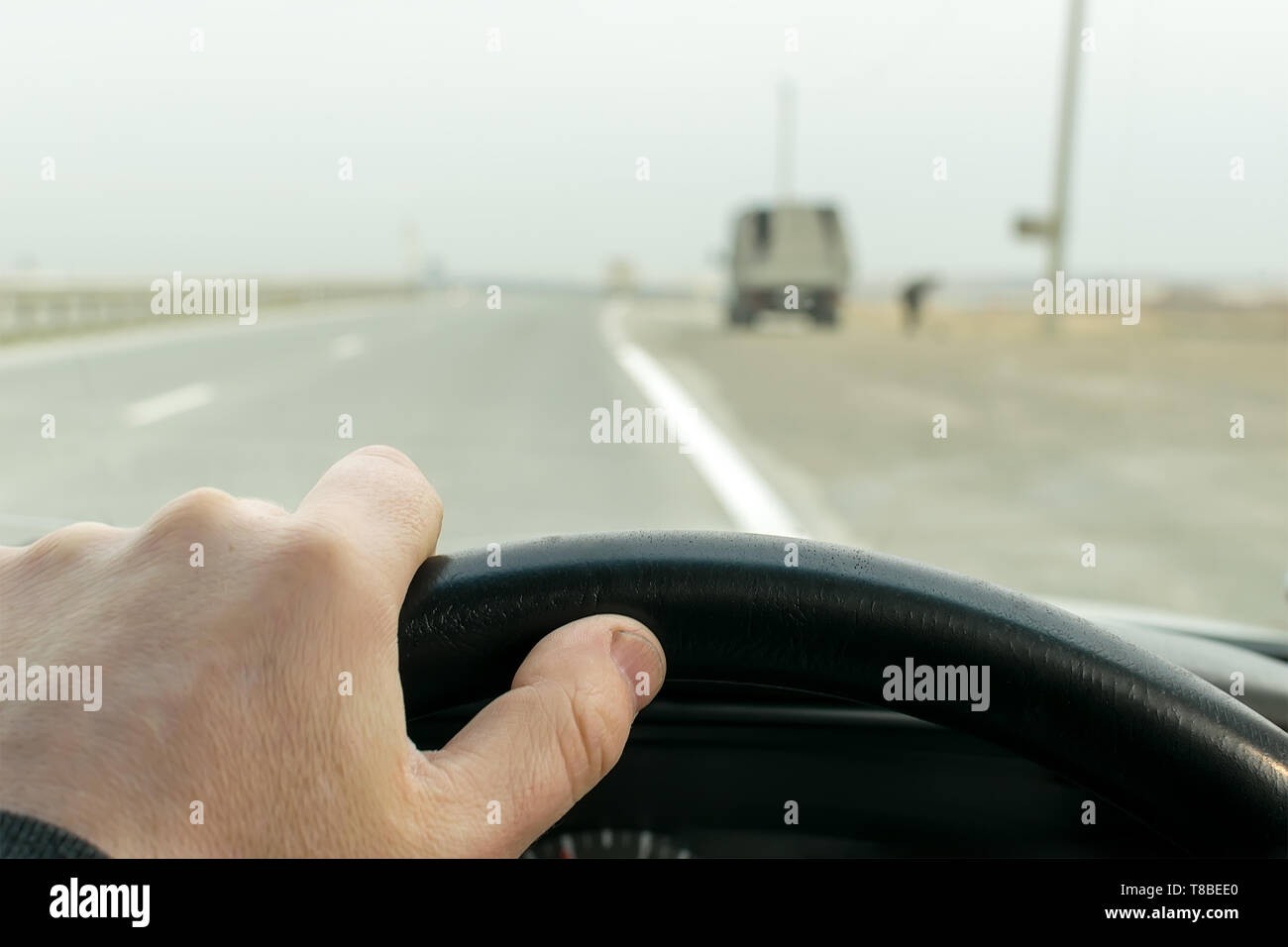 Vue sur les mains du conducteur sur le volant d'une voiture qui roule sur l'autoroute près de garé sur le côté du chariot Banque D'Images