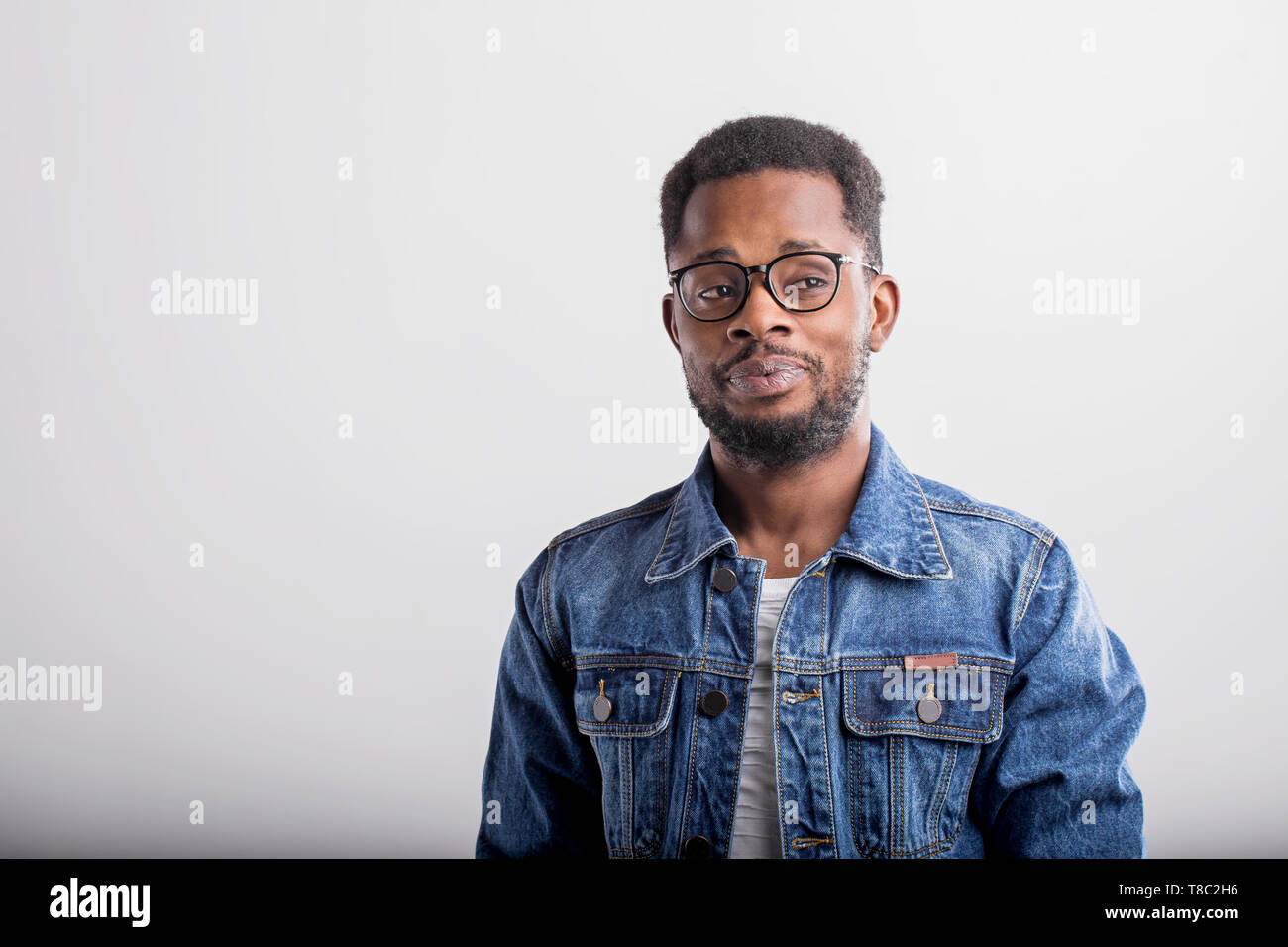 Portrait de bon à certain African American male avec petite barbe portant des T-shirt casual veste en jean et posant contre fond studio gris Banque D'Images
