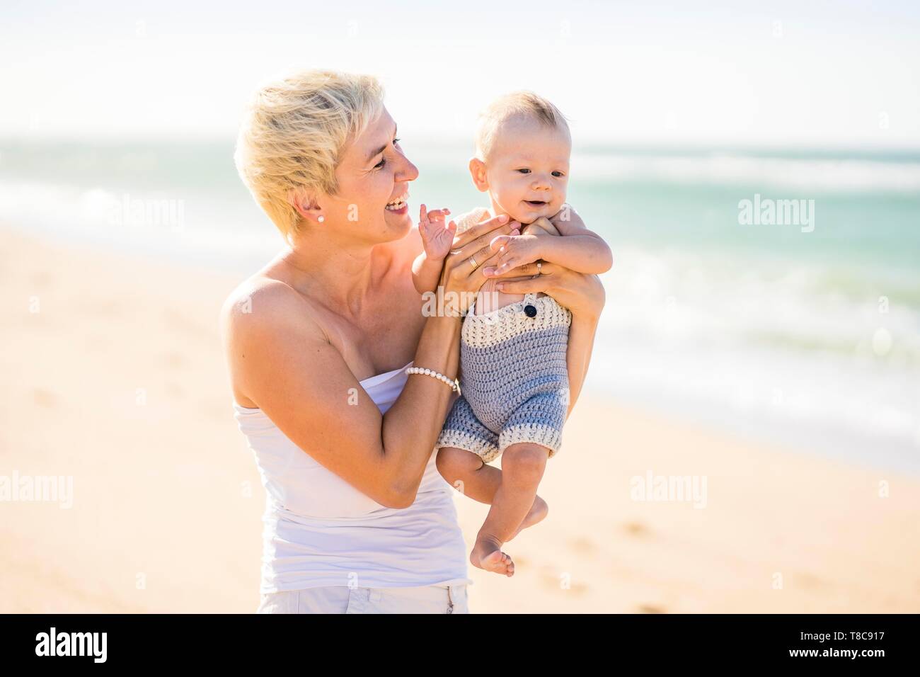 Belle mère blonde avec 4 mois bébé garçon sur la plage, Portugal Banque D'Images