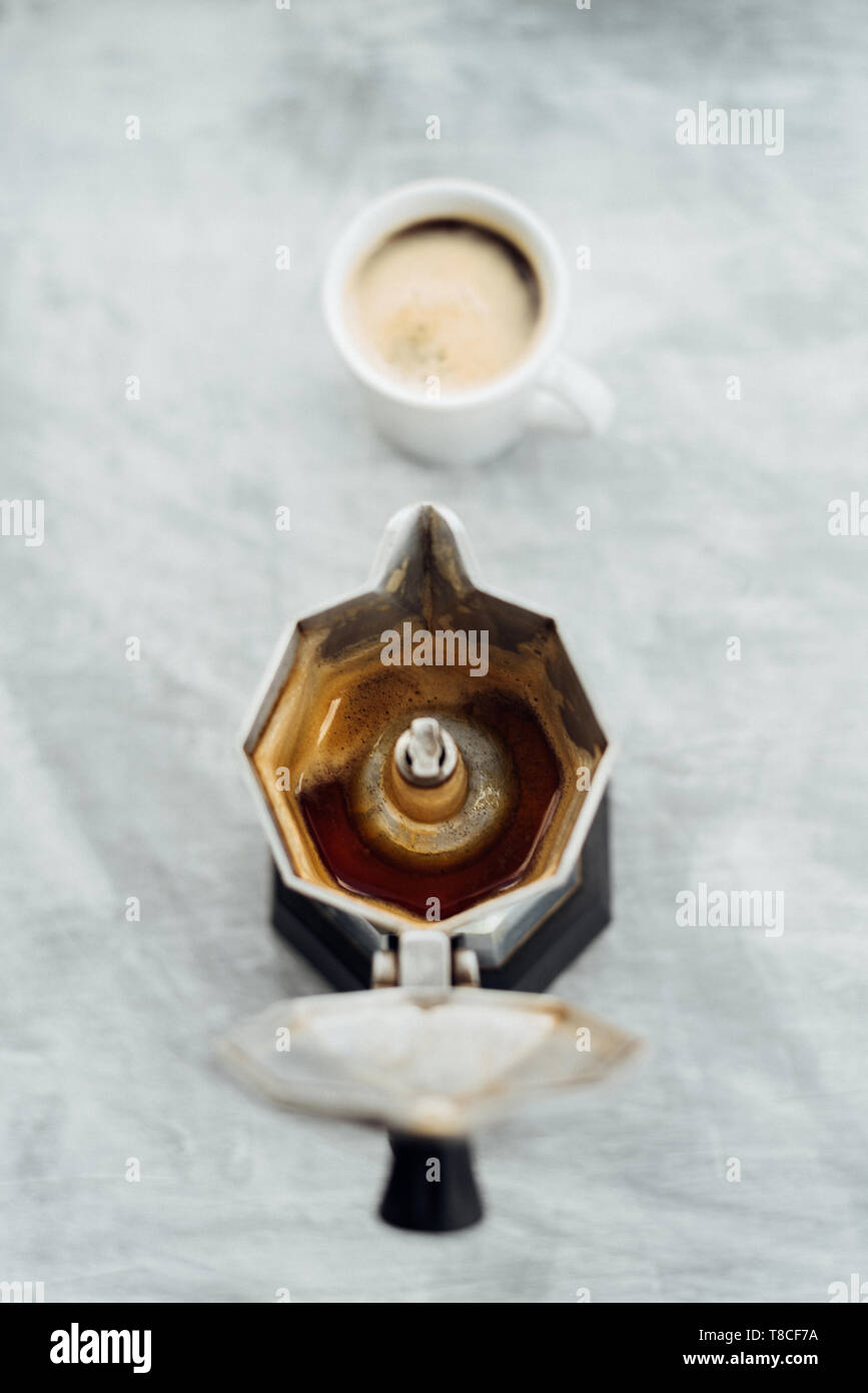Moka pot vide avec du café fraîchement moulu et pleine tasse sur fond gris Banque D'Images