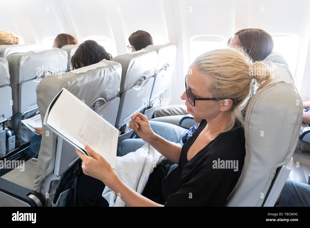 Woman Reading magazine sur l'avion pendant le vol. Female traveler lire assis dans passanger cabine. Banque D'Images