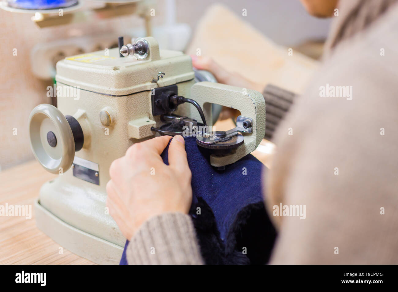 Professionnel hommes skinner, fourreur à l'aide de la machine à coudre spéciale pour coudre la peau de fourrure à l'atelier, atelier. La mode et le travail du cuir concept Banque D'Images