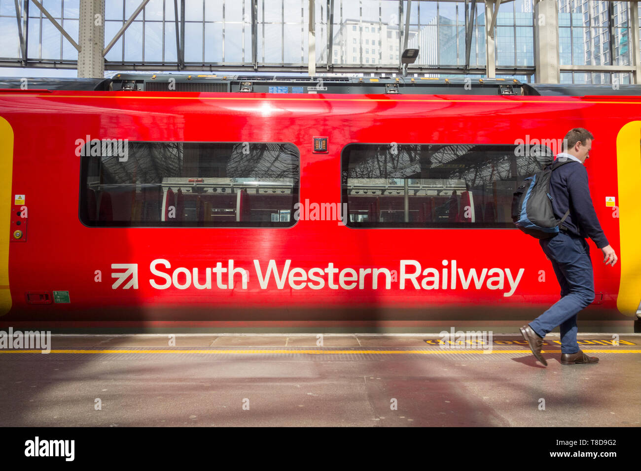Banlieue un homme passe devant un South Western Railway Transport à Londres Waterloo, UK Banque D'Images