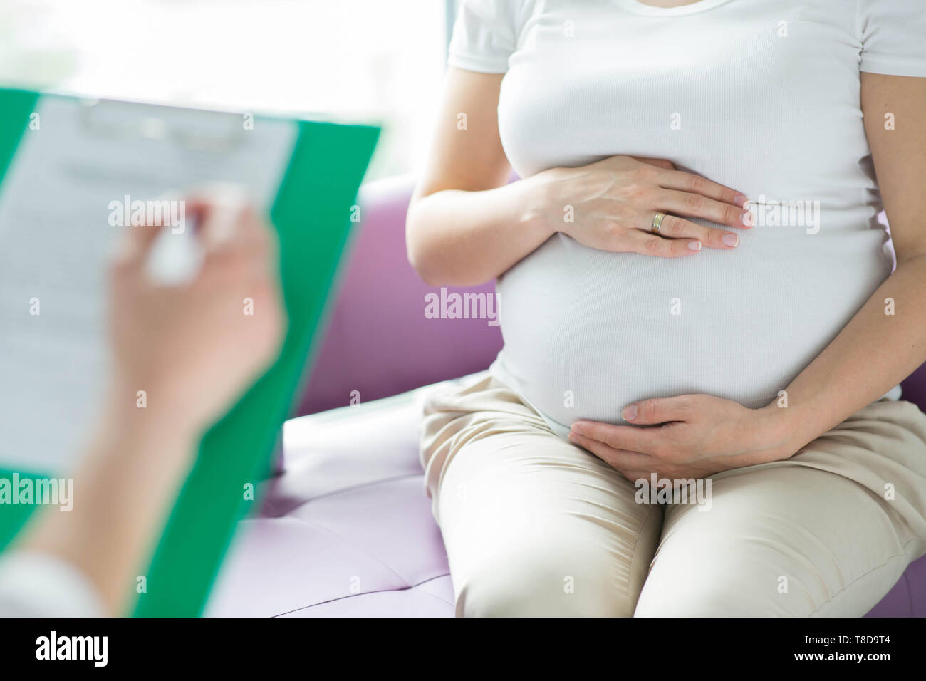 Woman is holding son estomac qui le médecin écrit sur une presse-papiers. Banque D'Images