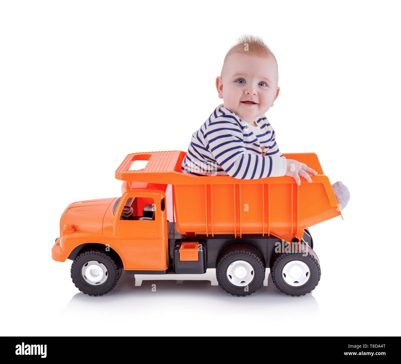 Happy Young boy sitting in open-box lit de camion benne jouet, isolé sur fond blanc avec ombre de réflexion. Tout-petit se trouve sur un camion dumper. Ador Banque D'Images