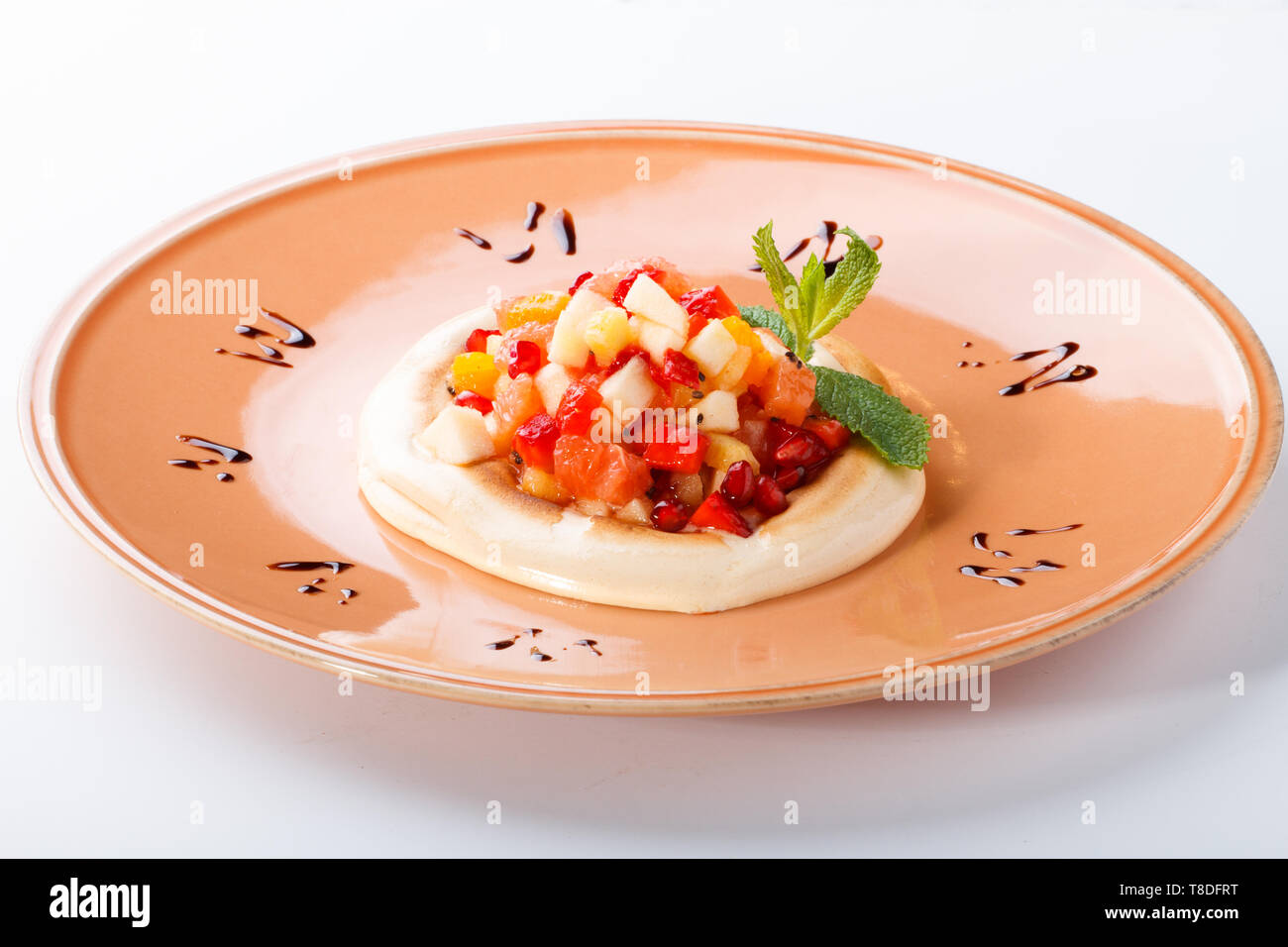Mélange de fruits de saison sur meringue caramel sur fond blanc. Banque D'Images