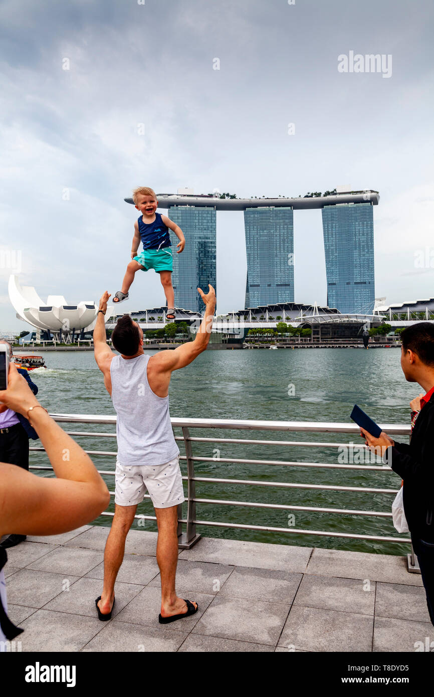 Un père jette son fils en l'air qui pose pour une photo à l'encontre de la skyline de Singapour, Singapour, en Asie du sud-est Banque D'Images