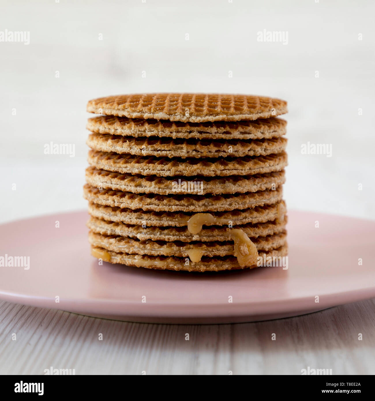 Pile de stroopwafels néerlandais doux au miel-caramel garniture sur une plaque rose, vue de côté. Close-up. Banque D'Images