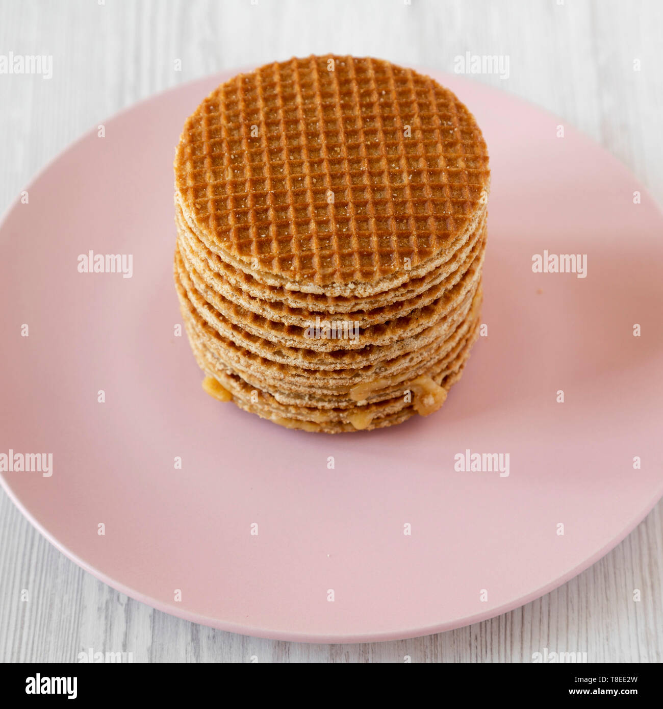 Pile de stroopwafels néerlandais savoureux avec du miel-caramel garniture sur une plaque rose, low angle view. Banque D'Images