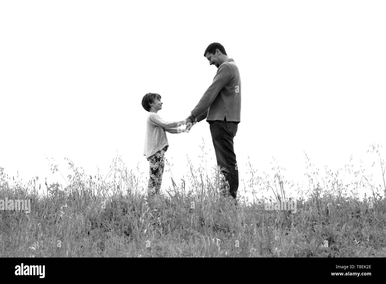 Le noir et blanc silhouette de père et fille à l'un l'autre tout en se tenant la main Banque D'Images