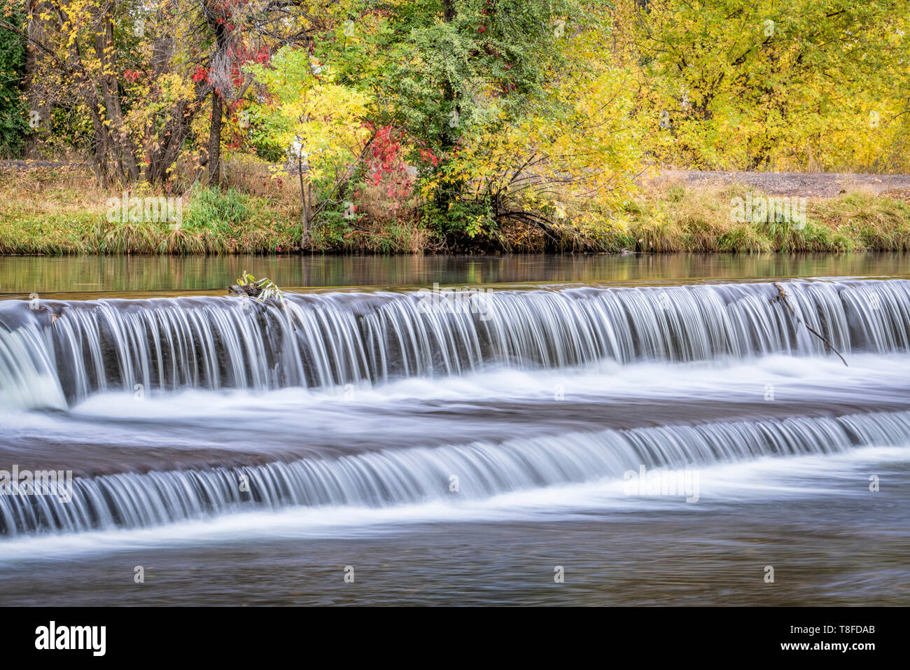 Au cours d'une cascade d'eau sur le barrage de dérivation de la rivière Powder avec couleurs d'automne au bakcground Banque D'Images