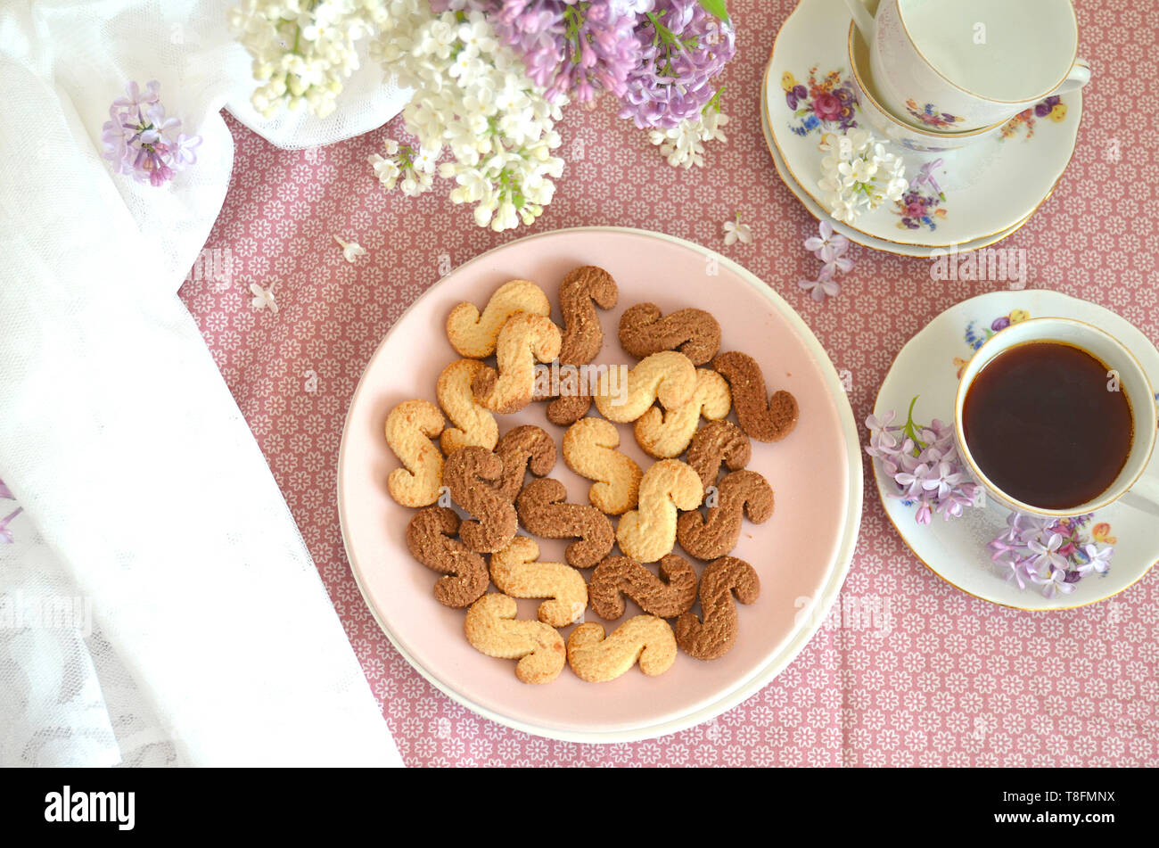 Tchèque traditionnel de la cannelle & cacao biscuits Esicka sur une plaque sur une table en bois avec un vieux-fashionned tasse de thé et de fleurs lilas. Banque D'Images