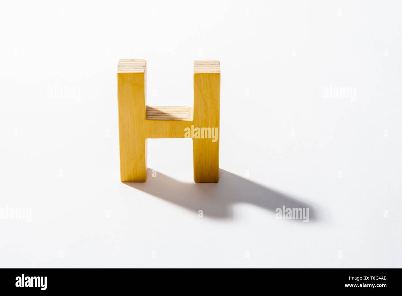 Alphabet en bois H et reflet de l'ombre. Banque D'Images