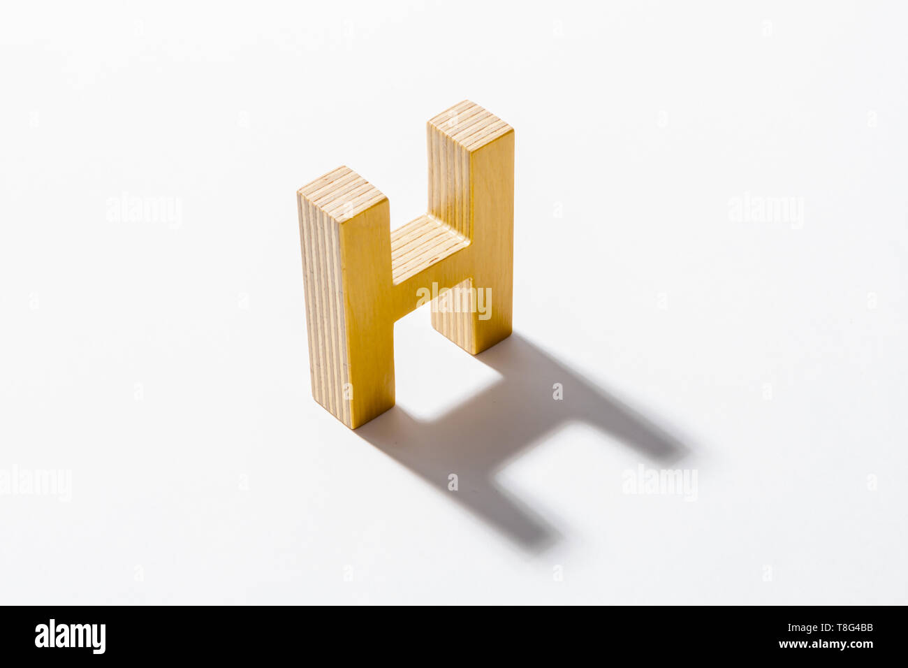 Alphabet en bois H et reflet de l'ombre. Banque D'Images