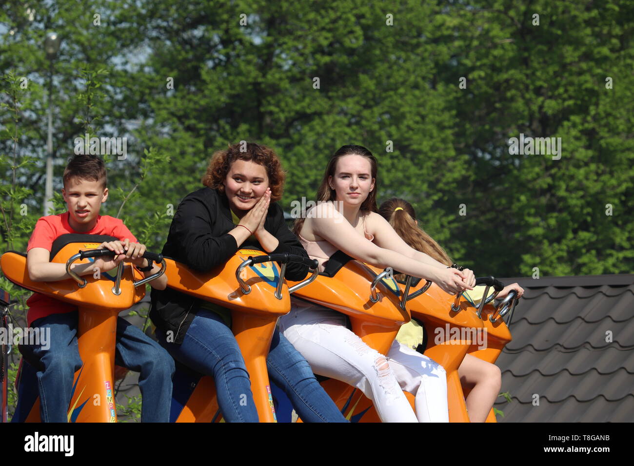 Moscou, Russie - Mai 2019 : Les gens s'amuser sur un voyage dans un parc d'amusement. Heureux les filles et garçon assis sur un carrousel en parc Sokolniki, loisirs en famille Banque D'Images