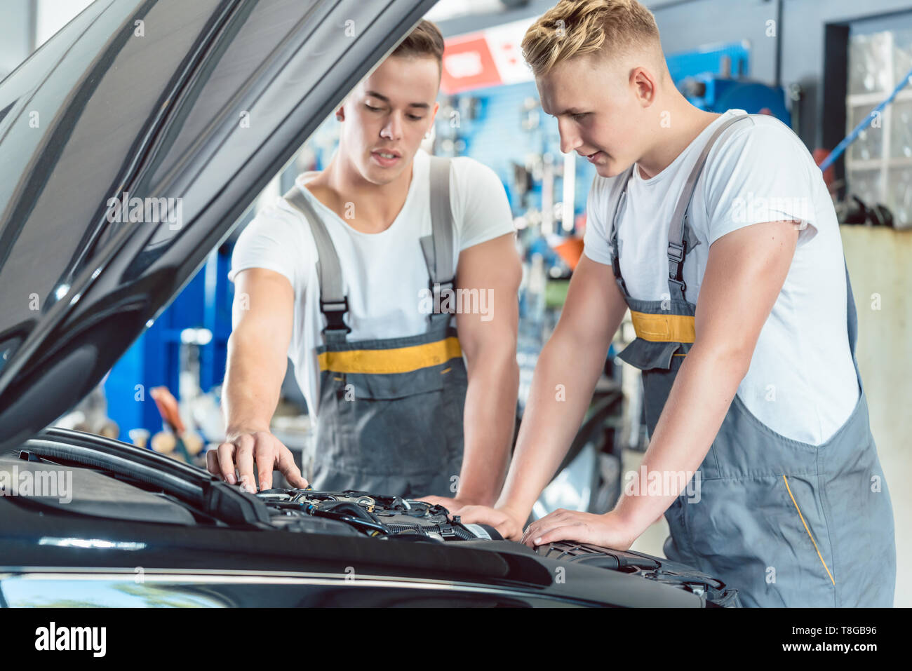 Mécanicien auto expérimenté contrôle les pièces d'une voiture dans un atelier de réparation moderne Banque D'Images